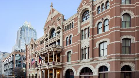 Photo of a grand, Edwardian/Victorian-style, four-story hotel built in 1886. A contemporary glass tower with a distinctive, angled top is in the background.