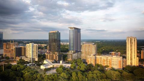 Photo composite of a riverside neighborhood with several tall existing buildings and renderings of two new, taller skyscrapers.