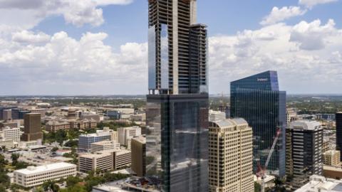 Photo of a very tall, glass walled skyscraper under construction.