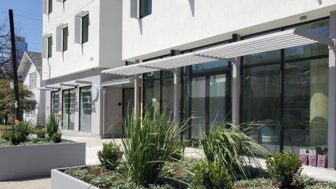 Photo of the exterior of a contemporary, simply designed building exterior showing street-level offices and the first two flors of apartments.