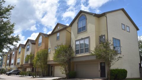 Photo of a row of contemporary three-story townhouses facing alley with garages on bottom floors.