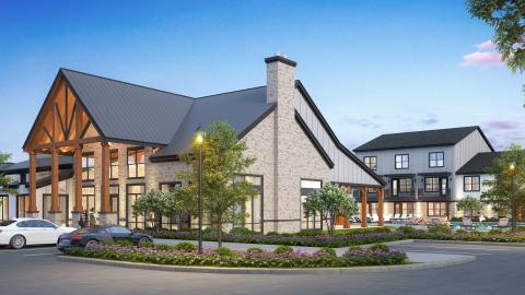 Photo of a new traditional-style apartment complex main building/clubhouse with two- and three-story residential buildings behind and circular driveway with one car in front.