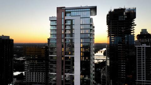 Drone photo of the top of glass- and concrete-clad tower at sunset.