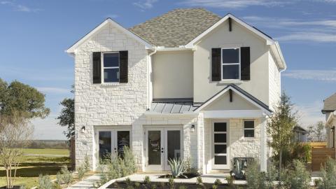 Two-story contemporary traditional model home clad in white stone or something that looks like stone.