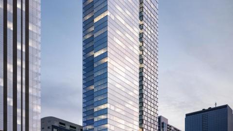Rendering of tall rectangular glass tower with feathery rooftop over deck and relatively small parking podium, bright lights on street level.